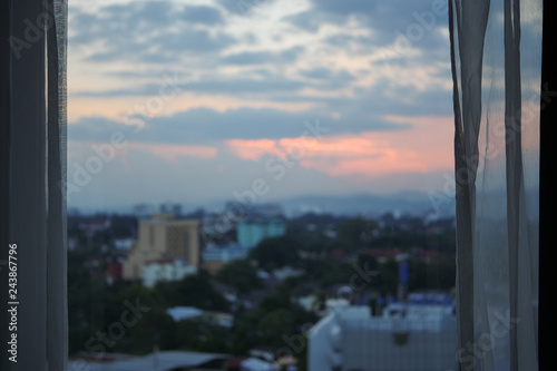 glass window with sunset sky in the city view outside the room