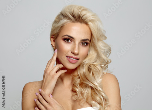 Blond bautiful woman touching her cheek isolated on gray background