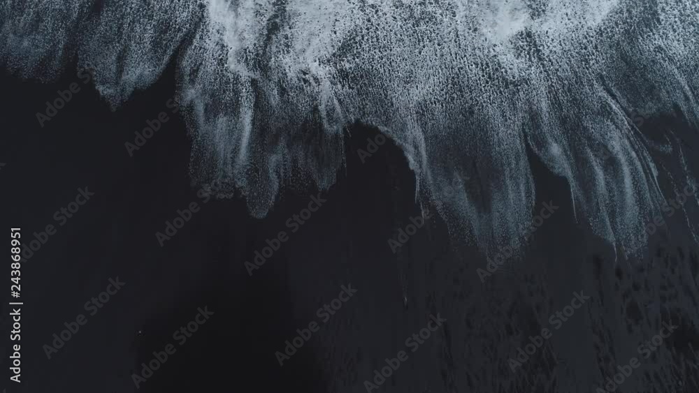 Waves break on a black sand beach on the coast of Maderia Island, Portugal