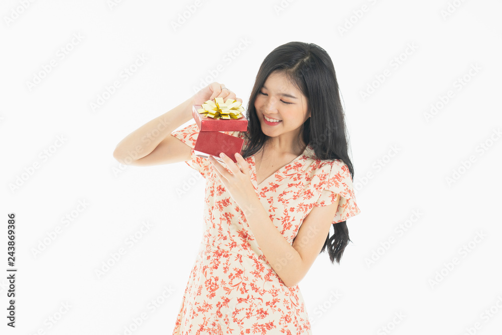 asian curious woman in red dress rejoicing her birthday or new year gift box. Young woman holding gift box with red bow being excited and surprised holiday present isolated white background asian curious woman in red dress rejoicing her birthday or new year gift box. Young woman holding gift box with red bow being excited and surprised holiday present isolated white background