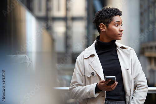 Photography Young black businesswoman standing in the city with smartphone in hand, close up