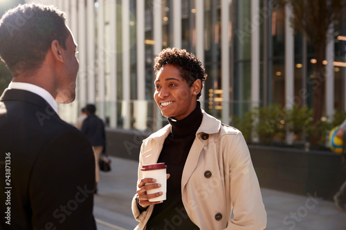 Canvas Print Young black businesswoman standing on the street with a takeaway coffee, talking