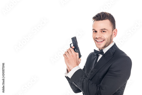 cheerful secret agent in black suit holding gun, isolated on white