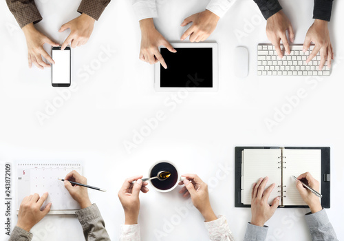 The view of businessmen working on desks with coffee mugs, calendars, digital tablets, smart phones, keyboards Computer, notebook