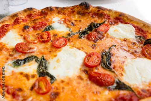 Delicious italian style pizza with tomatoes, mozarella and basil.