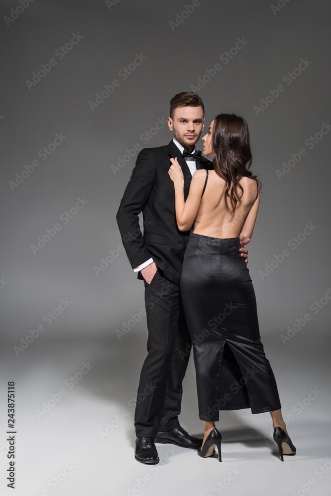beautiful elegant couple in black clothes hugging on grey beautiful elegant couple in black clothes hugging on grey