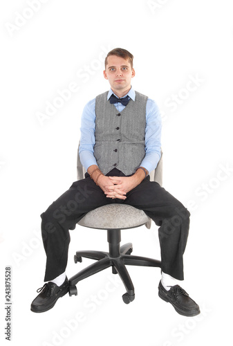 Man sitting in dress pants and vest, thinking