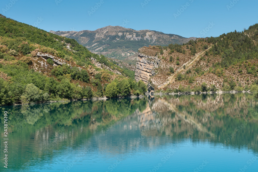 Lake of Castillon, a lake with mountains and green hills with a blue sky Lake of Castillon, a lake with mountains and green hills with a blue sky