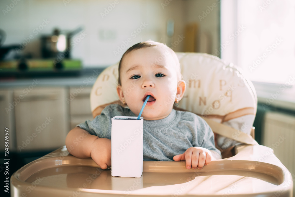 A child,  a girl drinking juice or milk with a tube of white packaging there is a place for the inscription