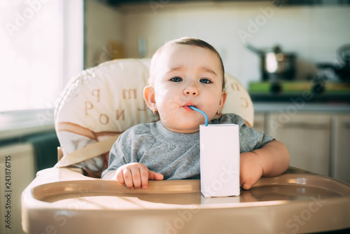A child,  a girl drinking juice or milk with a tube of white packaging there is a place for the inscription