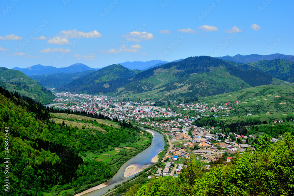 A small town divided by a river in the mountains. Bright summer day.