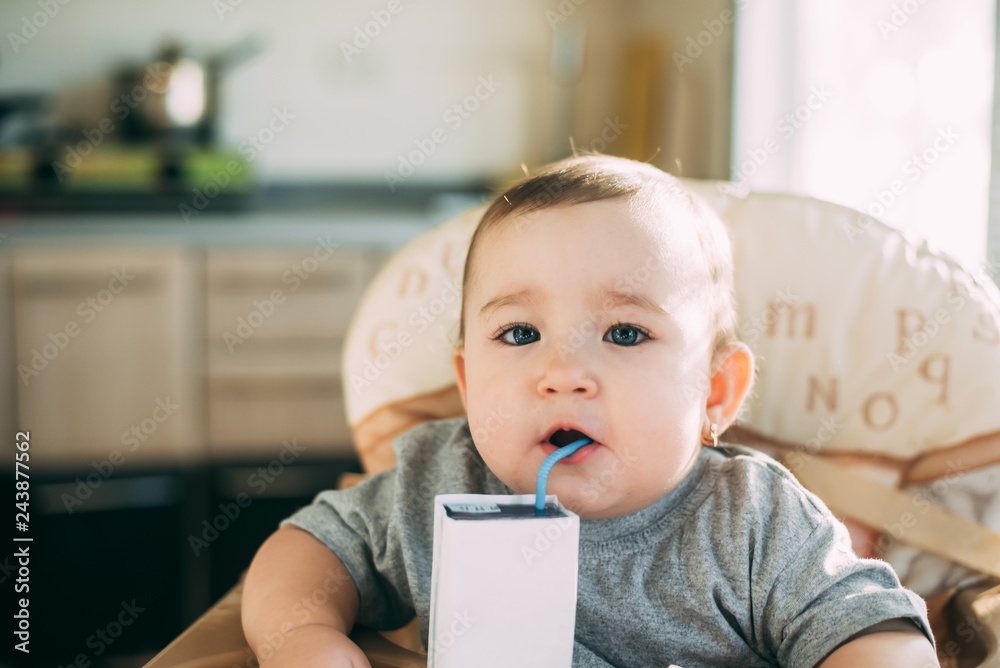 A child, a girl drinking juice or milk with a tube of white packaging there is a place for the inscription A child, a girl drinking juice or milk with a tube of white packaging there is a place for the inscription