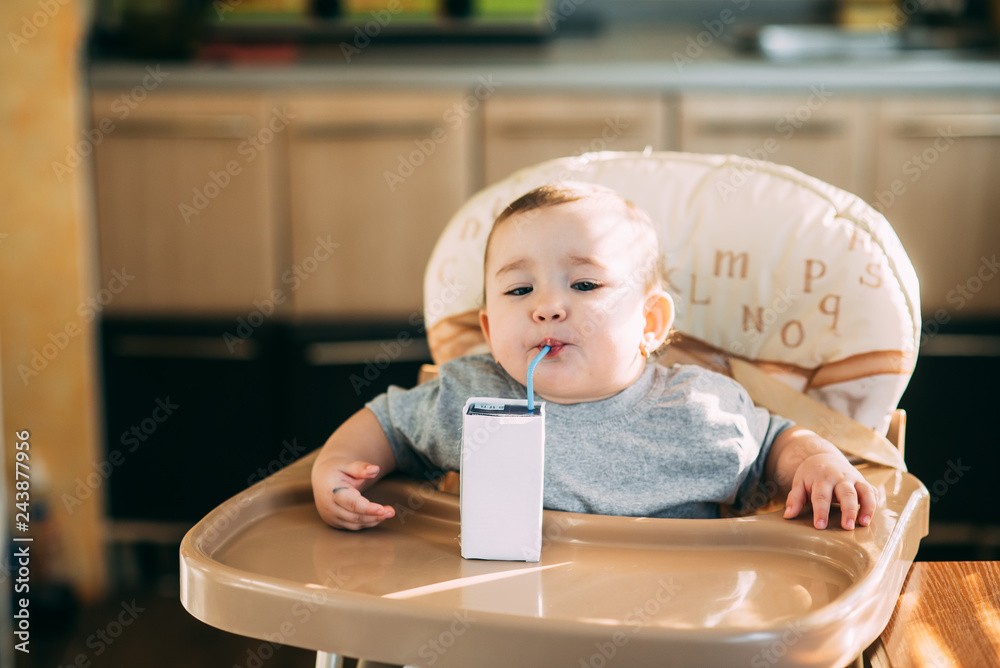 A child, a girl drinking juice or milk with a tube of white packaging there is a place for the inscription A child, a girl drinking juice or milk with a tube of white packaging there is a place for the inscription