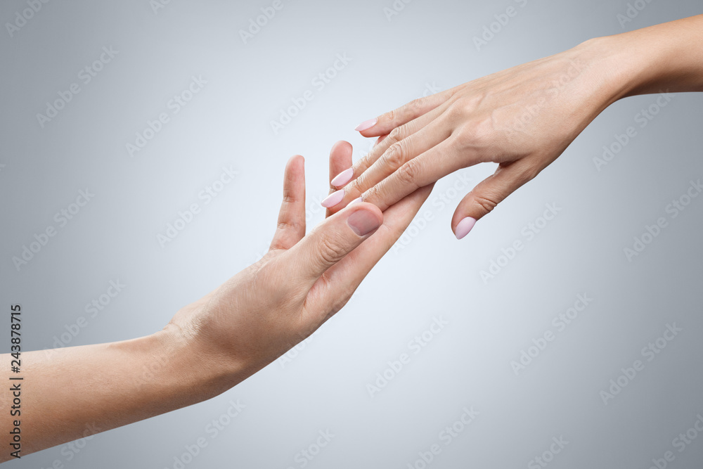 Male and female hands stretching towards each other on gray background