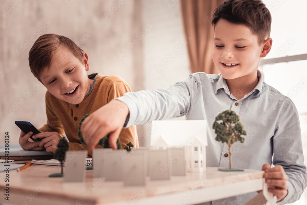 Two curious schoolboys building model of detached house Two curious schoolboys building model of detached house