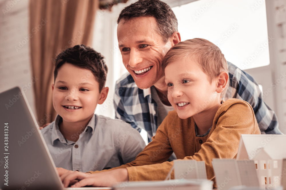 Smiling father feeling happy showing his children educational cartoon Smiling father feeling happy showing his children educational cartoon