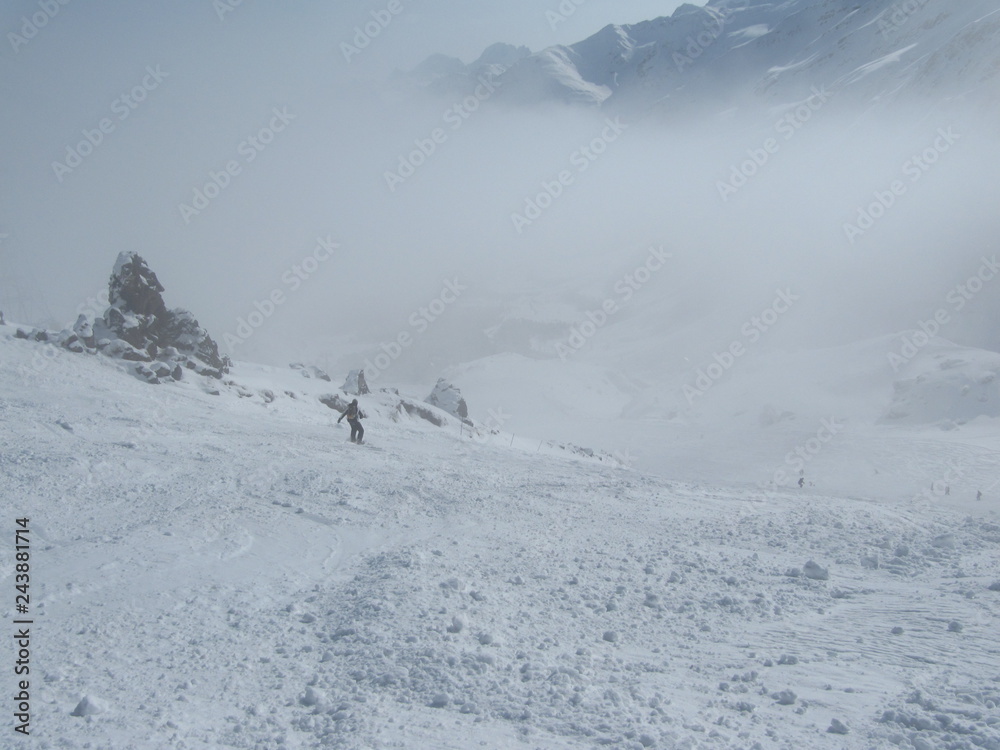 Skiers and snowboarders down the ski slope in a heavy fog.