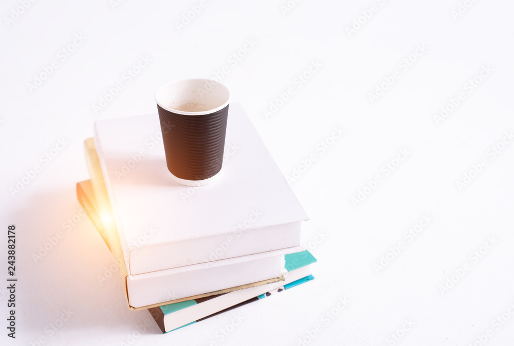 Fototapeta premium Coffee cup put on books stacked,blurry light around
