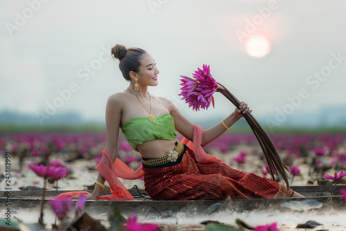 Traditional asian woman harvest red lotus flower in nature river, Thailand