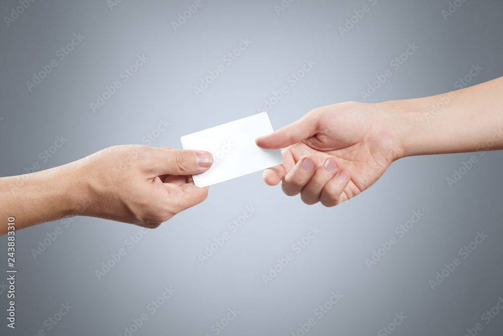 Obraz premium Hand giving a blank card or a ticket/flyer on grey background