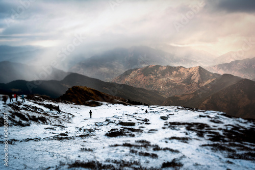Person standing alone on a snow clad terrain with mountain backdrop © Purush