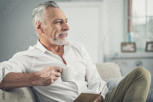 Beaming wrinkled man feeling cheerful having coffee break © zinkevych