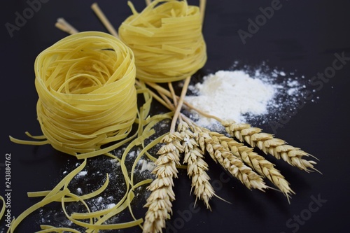 Pasta from durum wheat,the ears of corn on a black background.