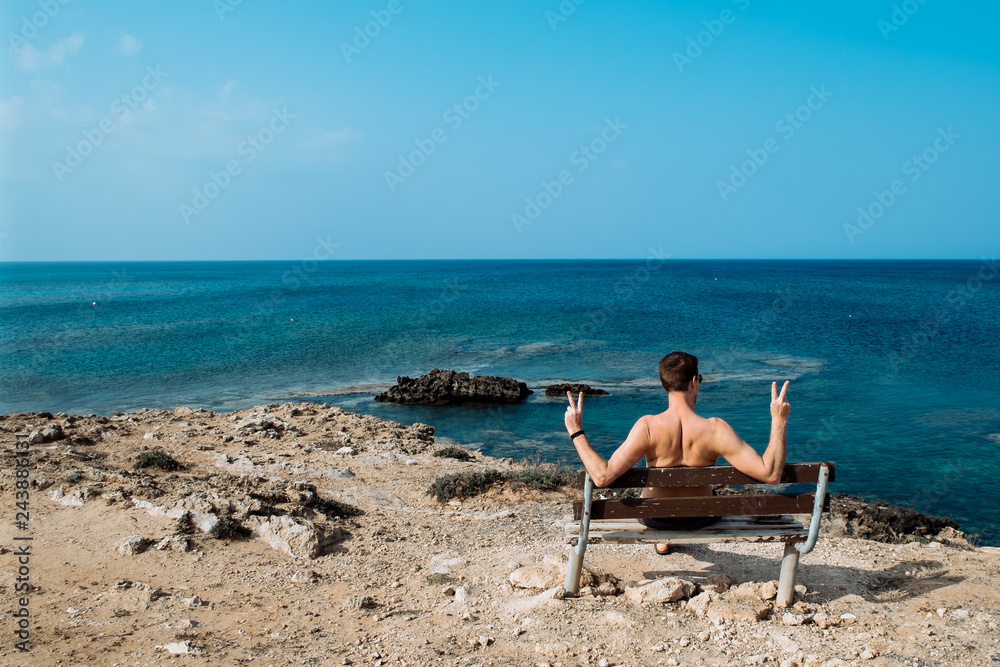 Rear view portrait of white man sitting relaxed on a bench and looking at the sea, man on a holiday. Cyprus