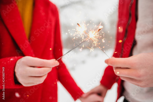 Sparklers and fireworks in the hands of a man and a woman close-up.