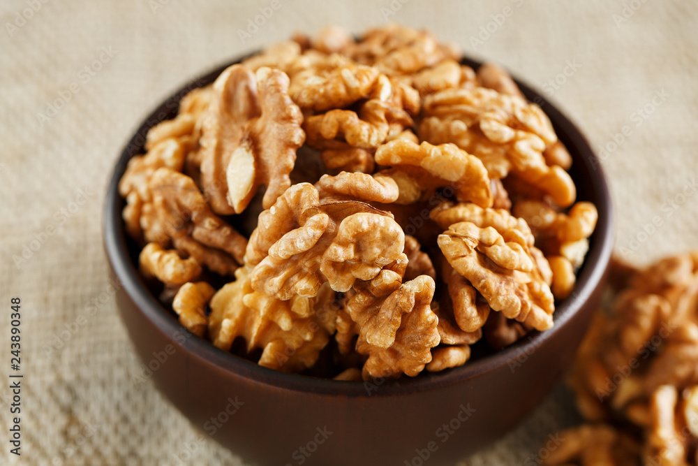 Peeled walnuts in a wooden, dark brown cup on a burlap cloth. Peeled walnuts in a wooden, dark brown cup on a burlap cloth.