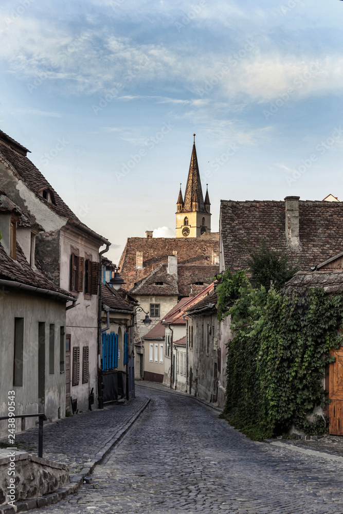 sibiu old city street with cobblestone pavement and church tower on background sibiu old city street with cobblestone pavement and church tower on background