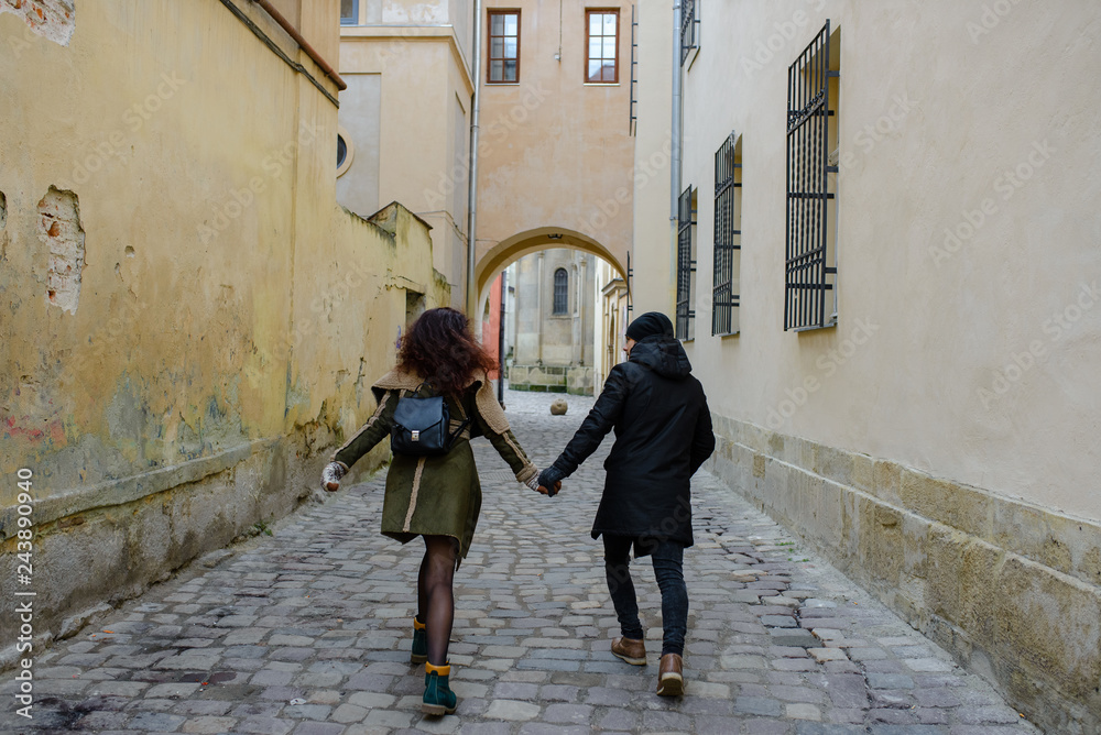 Young loving couple dressed in casual style walk at the old city in winter