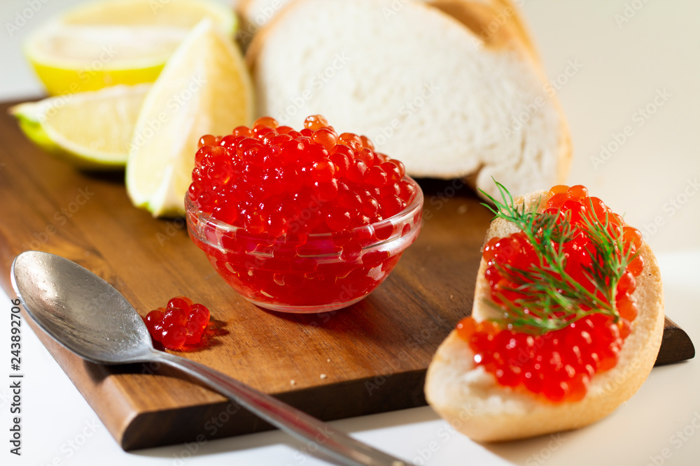 red caviar in glassware on wooden background with space for text