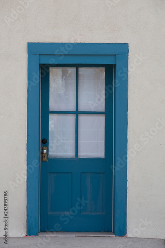 Blue door with glass and panels in a stucco wall