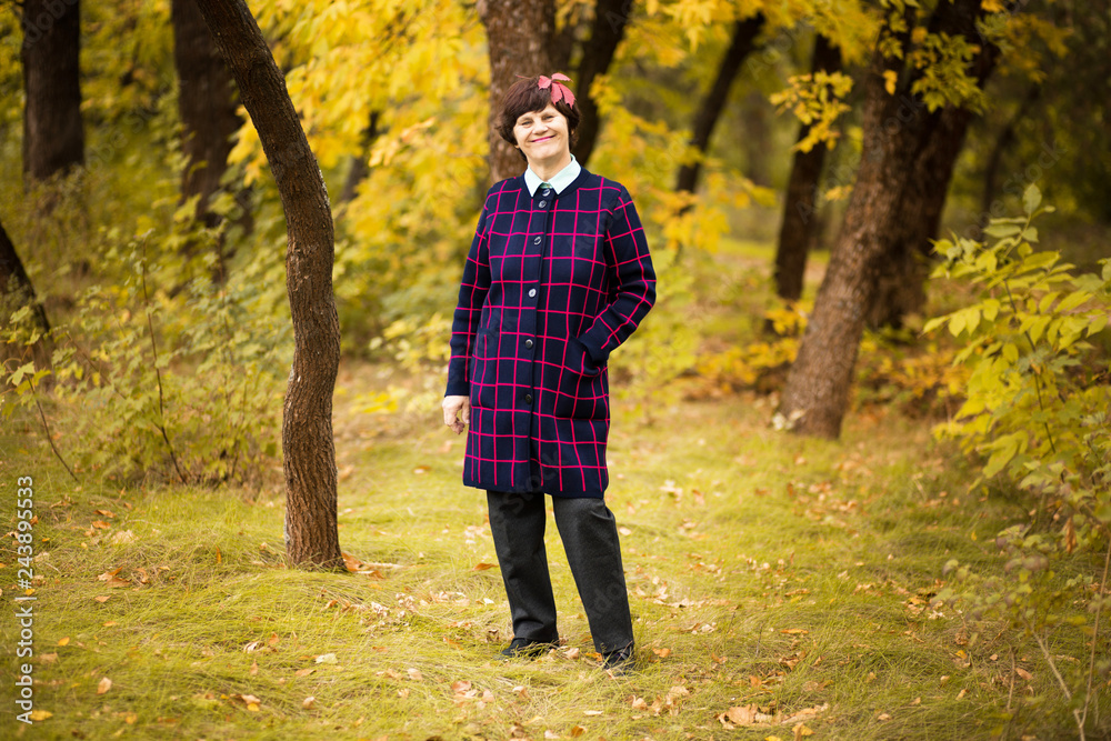 60 year old woman walk in gold autumn park