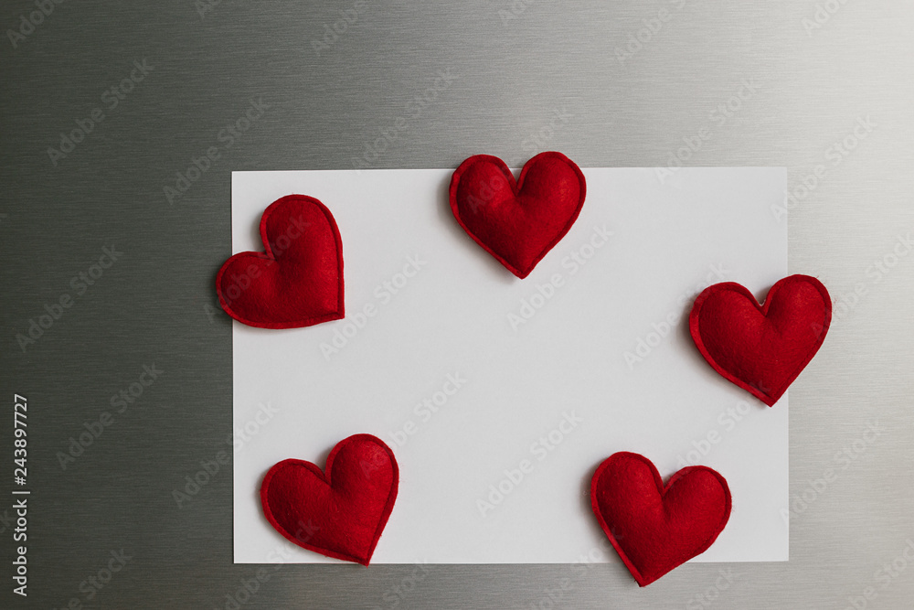 Handmade red felt heart shape magnets on refrigerator door.