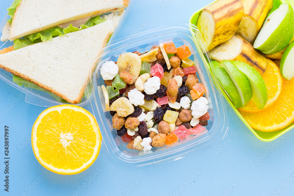 School lunch box. Bread, orange, candies, baby corns, carrot and tomatoes in green plastic container School lunch box. Bread, orange, candies, baby corns, carrot and tomatoes in green plastic container