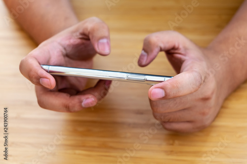 Two hands holding smart phone on wooden table