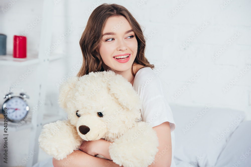 selective focus of smiling woman smiling and hugging teddy bear in bed selective focus of smiling woman smiling and hugging teddy bear in bed