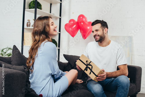 young man presenting gift box to girlfriend at valentines day