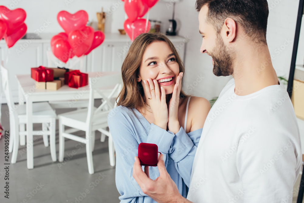 selective focus of surprised girl touching face while man doing proposal at valentines day selective focus of surprised girl touching face while man doing proposal at valentines day