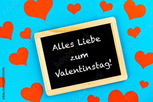 chalkboard with red hearts on a blue background with german text alles liebe zum Valentinstag, in english all love for valentines day