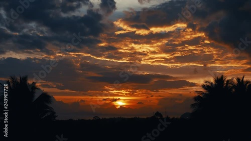 accelerated video of sunset, sunrise in jungle. silhouettes of palm trees on and a small strip of sea on the horizonte. time lapse clouds fly very quickly on background of sunset, sunrise. Change sky