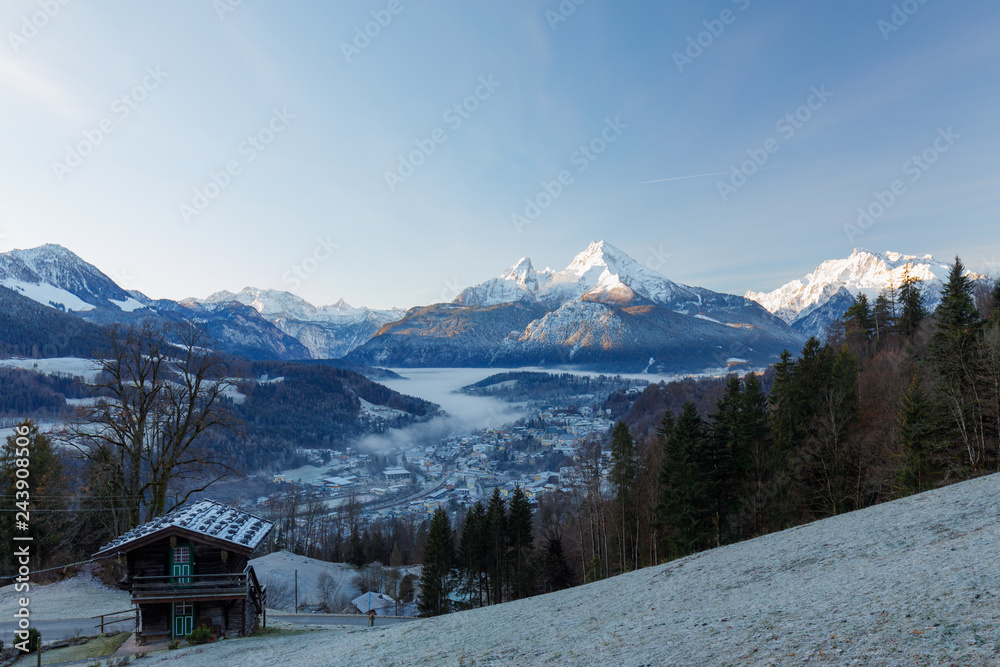 Berchtesgaden and Mountain Watzmann at sunrise in winter with small hut and fog in valley