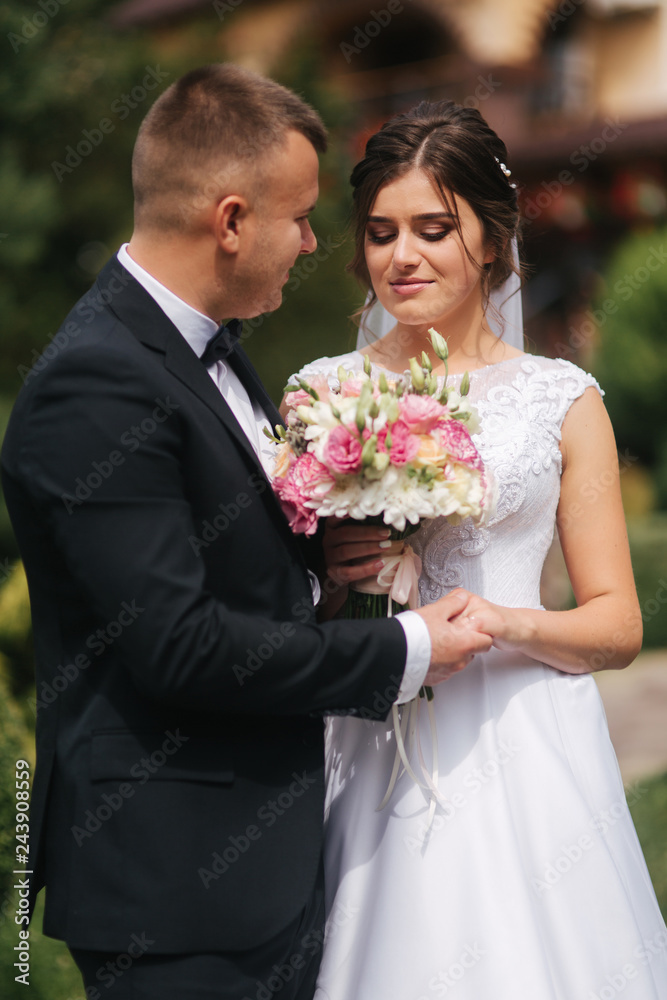 Gorgeous wedding couple walking on the back yard of couples house. Green background Gorgeous wedding couple walking on the back yard of couples house. Green background