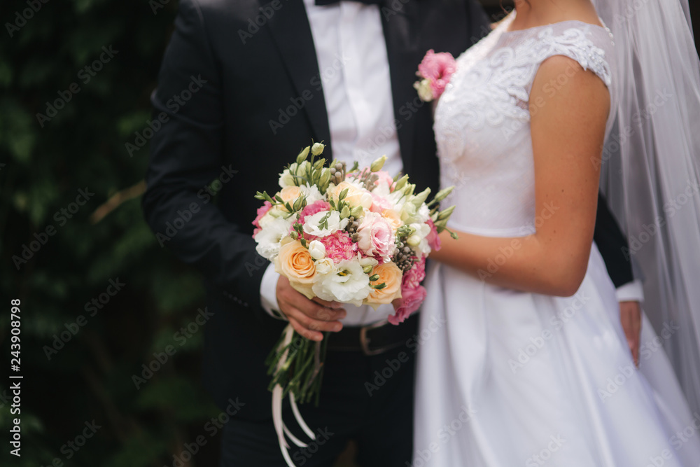 Wedding bouquet in brides hands. Close up view of couples hands holding wedding bouquet. Flowers Wedding bouquet in brides hands. Close up view of couples hands holding wedding bouquet. Flowers
