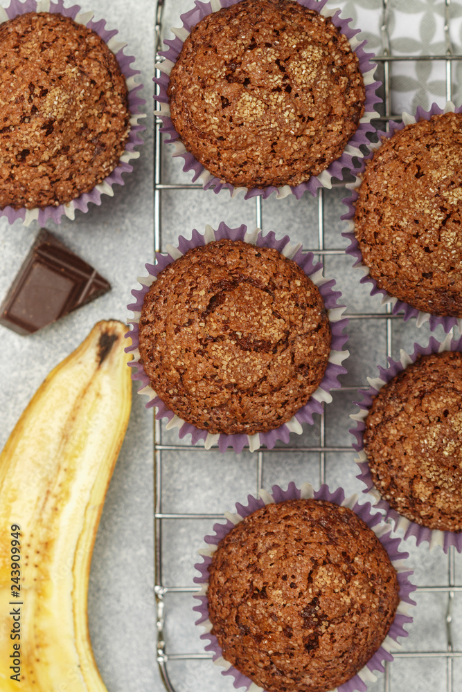Fototapeta premium Chocolate muffins with banana and sugar crust on the cooking grill. Fresh homemade pastry. Selective focus, top view