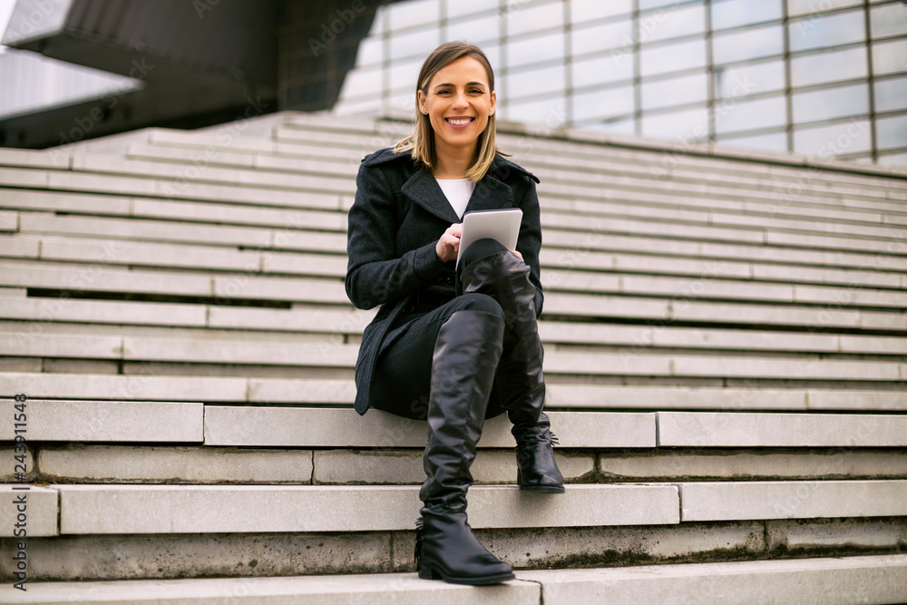 Beautiful businesswoman sitting on the staircase in the city and using digital tablet. Beautiful businesswoman sitting on the staircase in the city and using digital tablet.