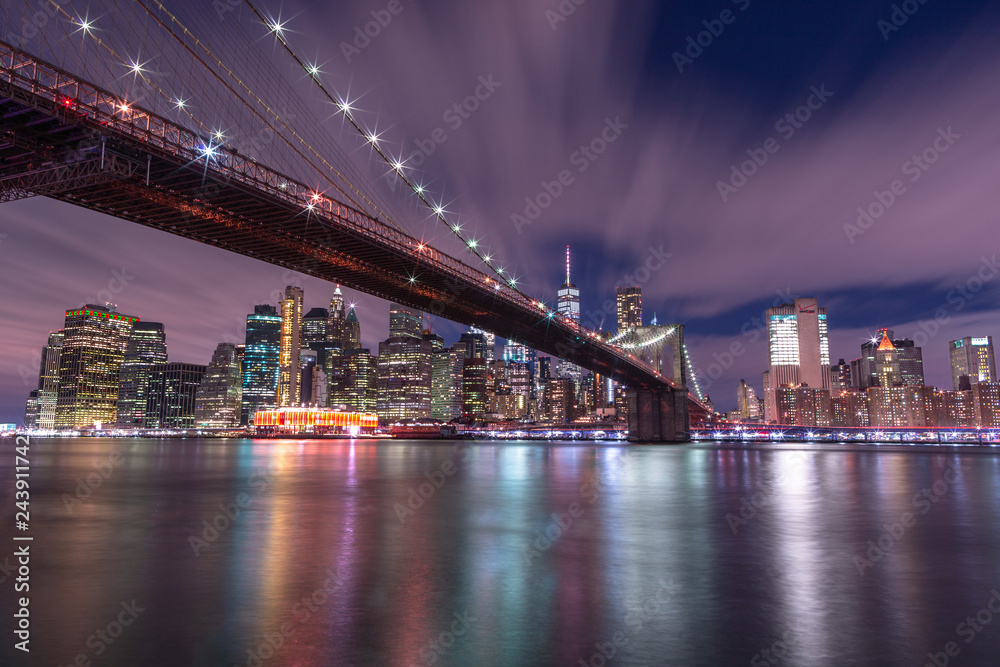 View on Financial district with Brooklyn bridge from east river at night with long exposure