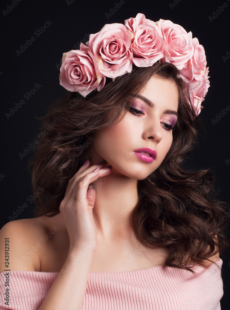 Portrait of young beautiful dark haired woman with magnificent rose wreath and gentle makeup on black background